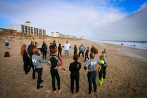 teens in wetsuits in a circle on beach