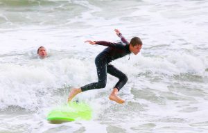 kid jumping off surfboard in wetsuit