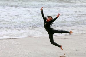kid jumping up in ocean in wetsuit