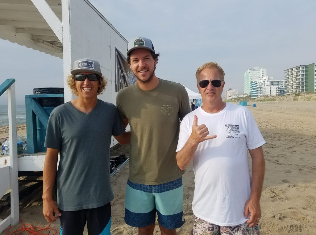 three surfer dudes on beach