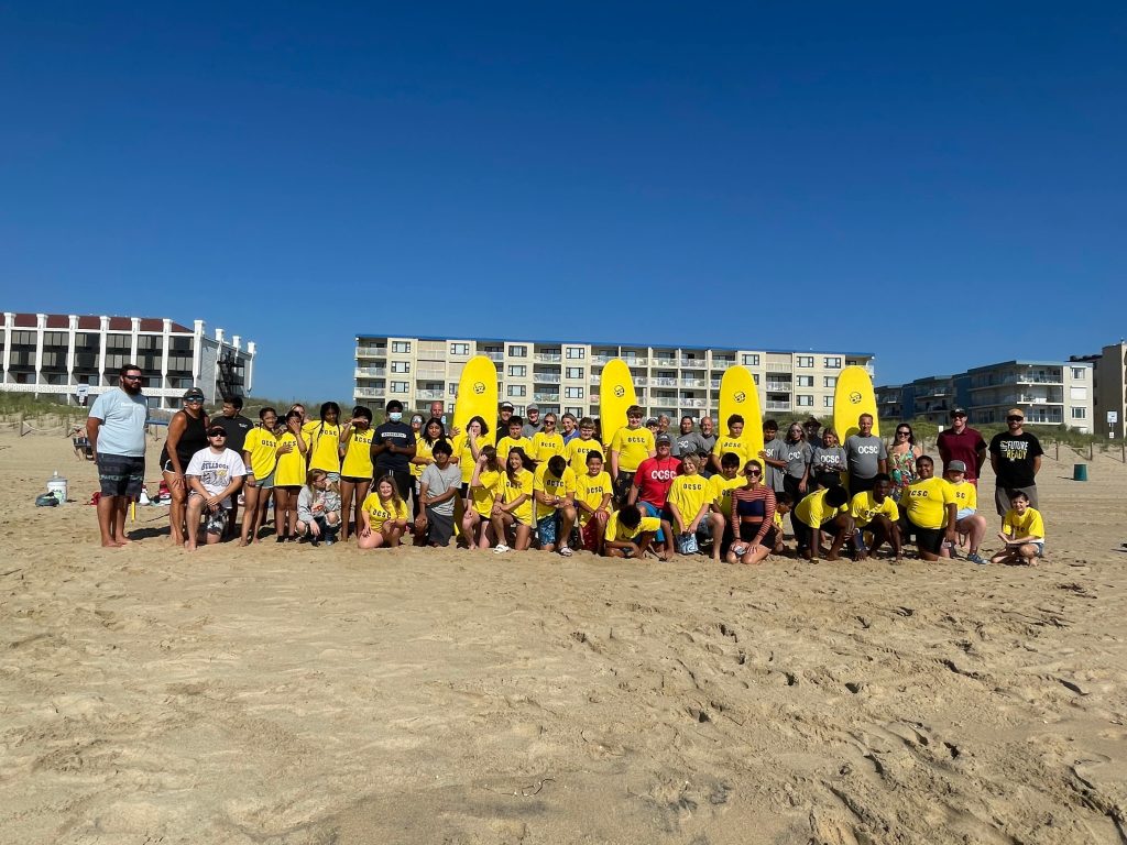 Picture of surf students and volunteers on beach.